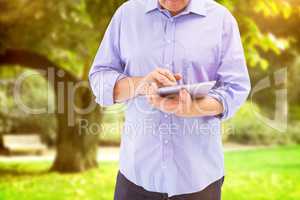 Composite image of mature man using his tablet pc