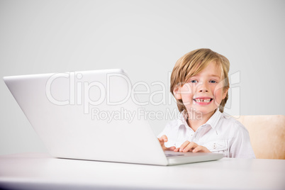 Composite image of cute boy using laptop