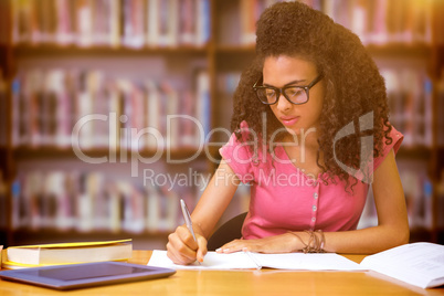 Composite image of student sitting in library writing