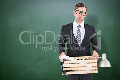 Composite image of sad geeky businessman holding box of his thin