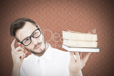 Composite image of geeky young man looking at pile of books