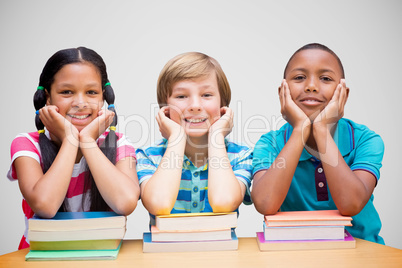 Composite image of cute pupils looking at camera in library