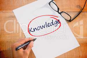 Knowledge against left hand writing on white page on working des