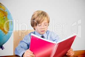 Composite image of cute pupil reading at desk