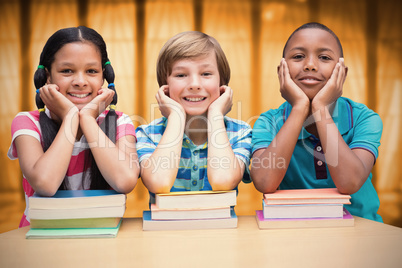 Composite image of cute pupils looking at camera in library