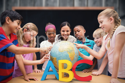 Composite image of cute pupils and teacher looking at globe in l