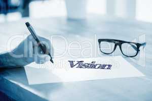 Vision  against side view of hand writing on white page on worki