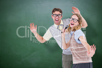 Composite image of geeky hipster couple singing into a microphon