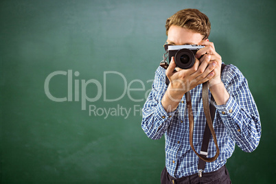 Composite image of geeky hipster holding a retro camera