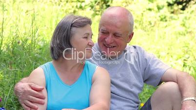 Senior couple sitting on grass together relaxing