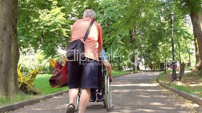 Senior man walking with disabled young man