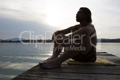 Young man sitting at a bridge in evening light