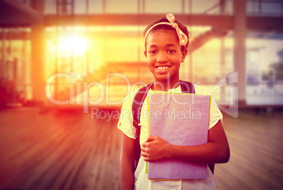 Composite image of little girl holding folders in school corrido