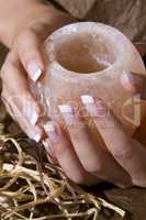 Woman?s hand with French manicure holding exotic salt-crystal candlestick