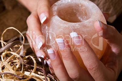 Woman?s hand with French manicure holding exotic salt-crystal candlestick