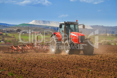 Brand new red tractor on the field working on land