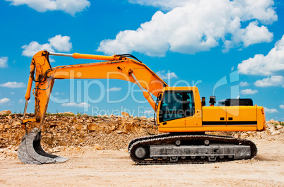 Yellow excavator on a construction site against blue sky
