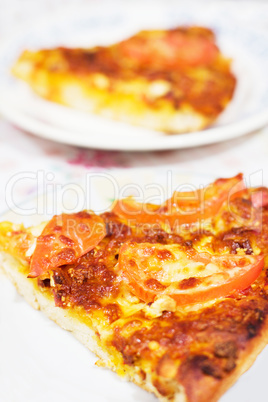 A slice of pizza with tomato and cheese on plate