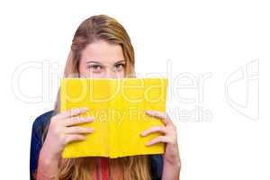 Composite image of student covering face with book in library