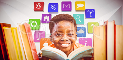 Composite image of cute boy reading book in library