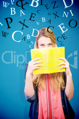 Composite image of student covering face with book in library