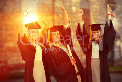 Composite image of three students in graduate robe raising their