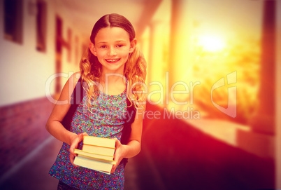 Composite image of cute little girl holding books in library