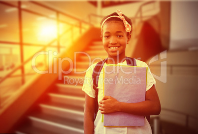 Composite image of little girl holding folders in school corrido