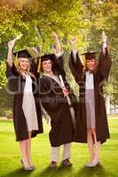 Composite image of three students in graduate robe raising their