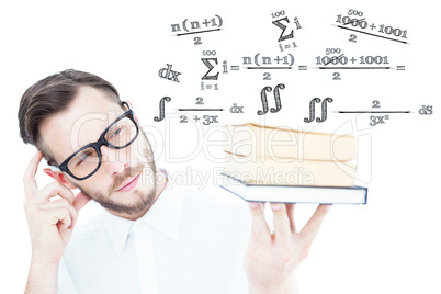 Composite image of geeky young man looking at pile of books