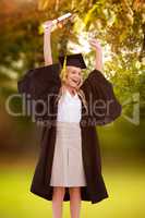 Composite image of blonde student in graduate robe holding up he