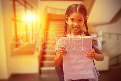 Composite image of cute pupil smiling at camera holding notepad