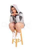 Girl sitting on chair in gray hoodie.