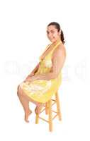 Woman in yellow dress sitting on chair.
