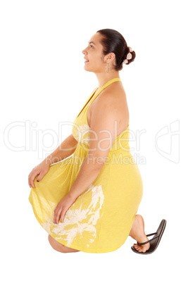 Pretty woman in yellow dress kneeling.
