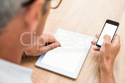 Casual businessman using smartphone and tablet