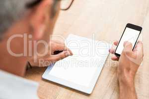 Casual businessman using smartphone and tablet
