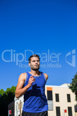 Handsome athlete jogging against blue sky