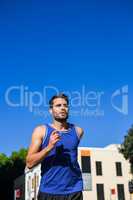 Handsome athlete jogging against blue sky