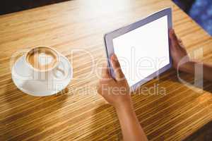 A businesswoman using a tablet and enjoying a coffee