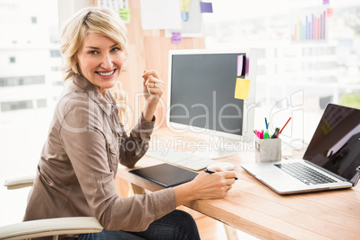 Smiling casual designer sitting at desk Smiling casual designer sitting at desk
