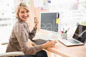 Smiling casual designer sitting at desk