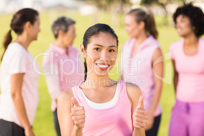 Smiling woman wearing pink for breast cancer in front of friends