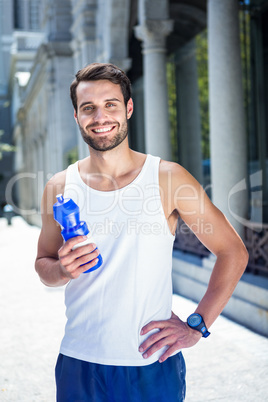 Smiling handsome athlete holding bottle