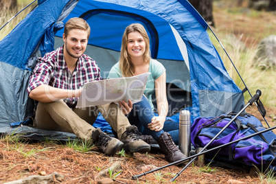 Young pretty hiker couple sitting in a tent looking at map