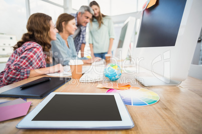 Tablet in the foreground with business people in the background