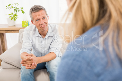 Worried man sitting on couch and talking to therapist