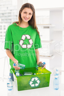 Smiling eco-minded brunette holding recycling bottles