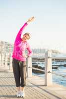 Smiling sporty woman stretching at promenade