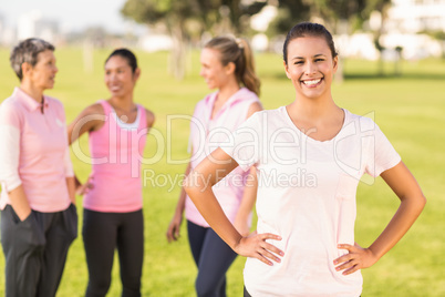 Smiling brunette wearing pink for breast cancer in front of frie